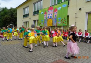 Taras przedszkolny, a na nim scenografia przedstawiająca zamek. Dzieci tańczą w parach, jedna dziewczynka tańczy sama i spogląda w bok.